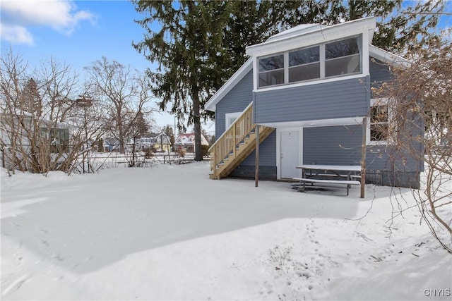 snow covered house featuring stairs