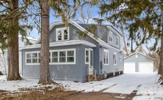 view of snowy exterior featuring a garage, entry steps, and an outbuilding