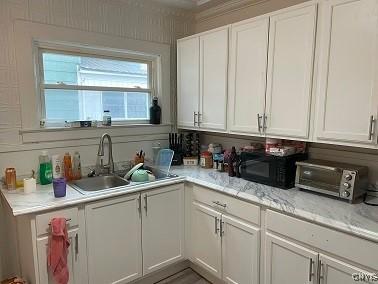 kitchen featuring light countertops, black microwave, white cabinets, and a sink