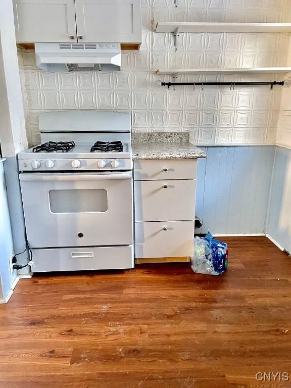 kitchen featuring under cabinet range hood, white gas range oven, white cabinetry, and dark wood-style flooring