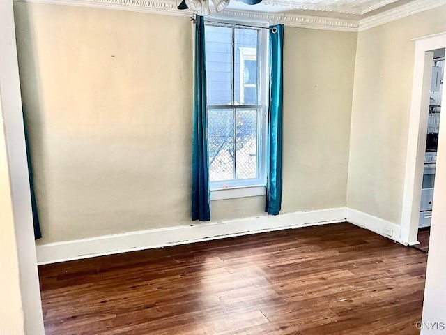 spare room with ornamental molding, baseboards, and wood finished floors