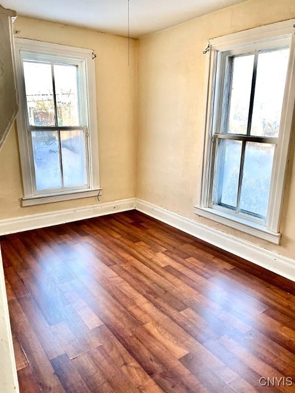 spare room with dark wood-style flooring and baseboards