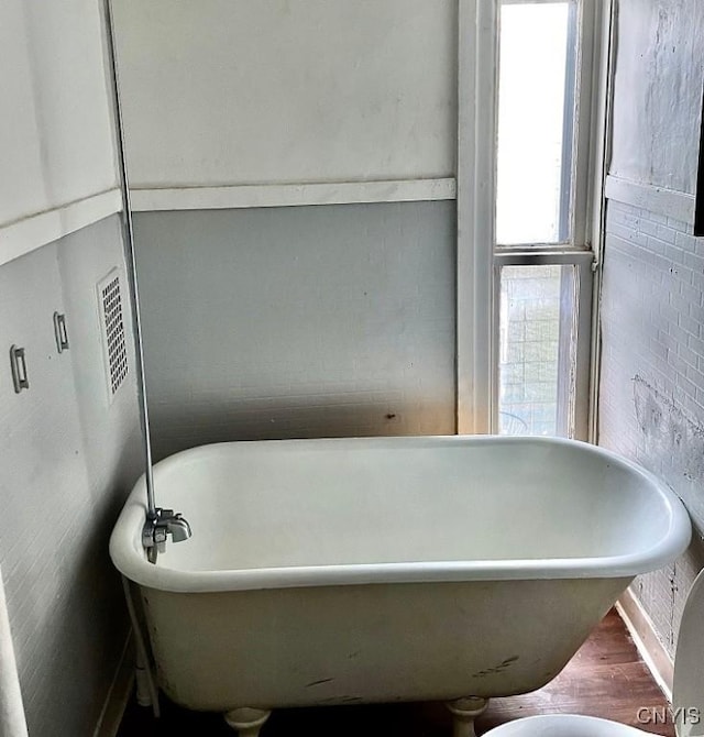 bathroom with a freestanding tub and wood finished floors