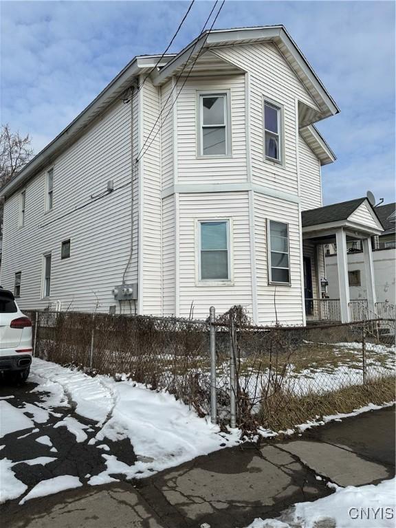 view of snow covered exterior with a fenced front yard