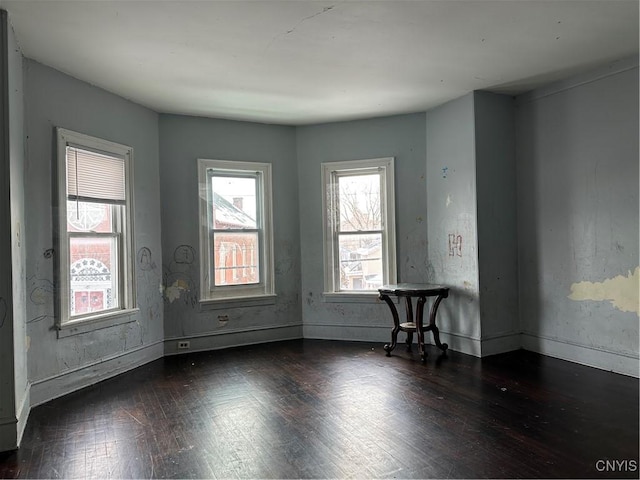 empty room with wood-type flooring and baseboards