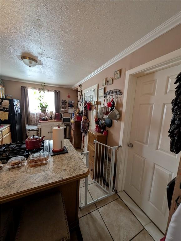 kitchen featuring light tile patterned floors, light countertops, ornamental molding, freestanding refrigerator, and gas cooktop