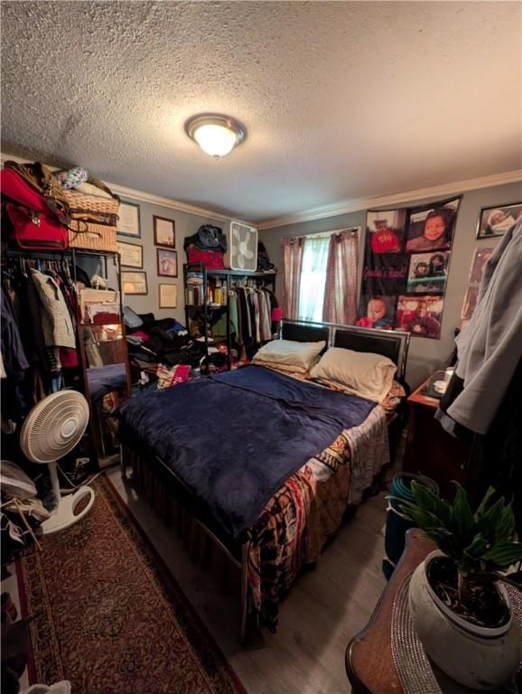 bedroom with ornamental molding, a textured ceiling, and wood finished floors