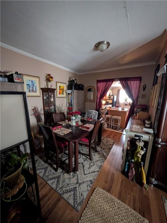 dining room featuring a textured ceiling, wood-type flooring, and crown molding