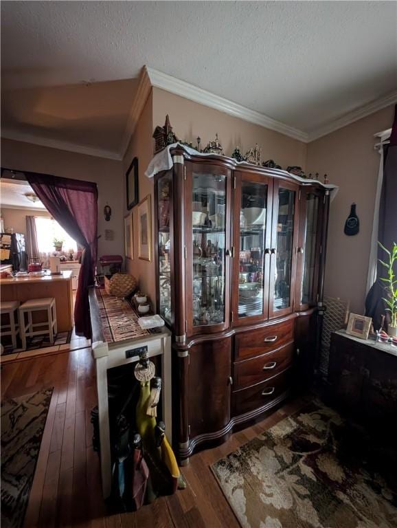 interior space with a textured ceiling, ornamental molding, and wood finished floors