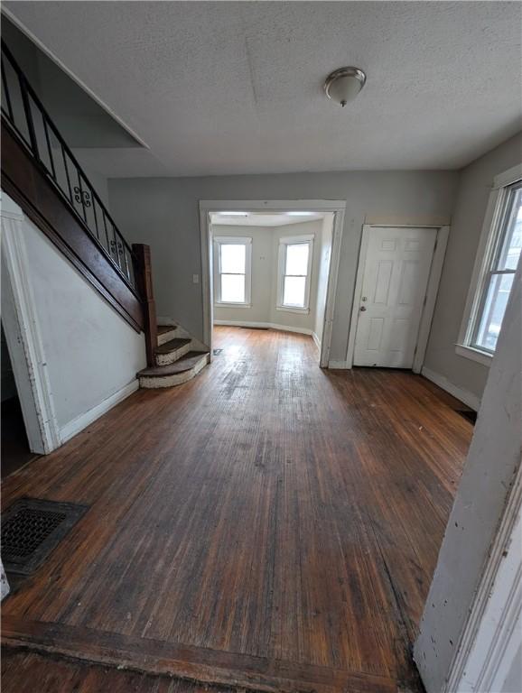 entryway with visible vents, a textured ceiling, wood finished floors, baseboards, and stairs