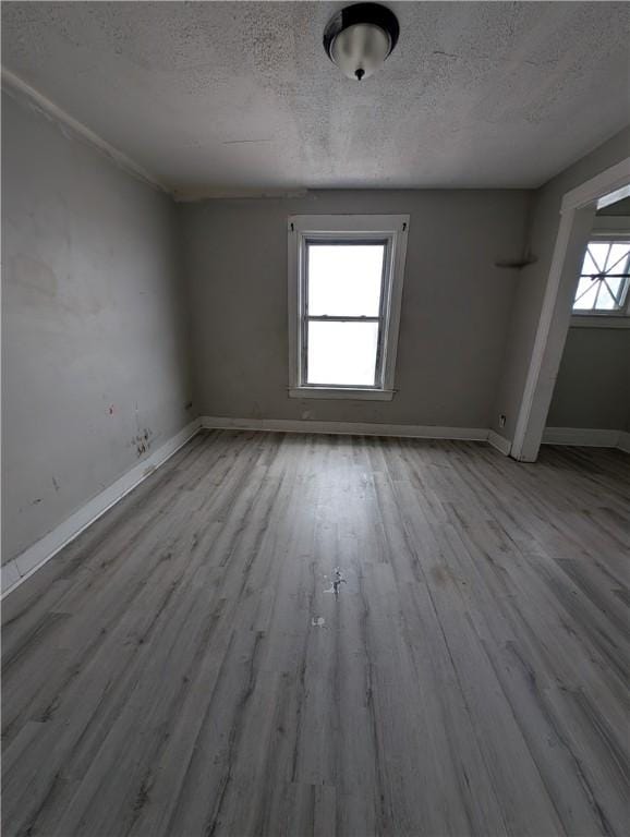 unfurnished room featuring a textured ceiling, baseboards, and wood finished floors