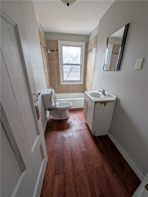 full bath featuring shower / washtub combination, toilet, vanity, wood finished floors, and baseboards