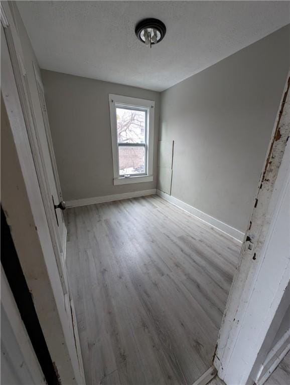 interior space with a textured ceiling, wood finished floors, and baseboards