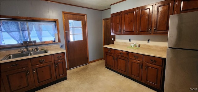 kitchen featuring ornamental molding, freestanding refrigerator, light countertops, light floors, and a sink