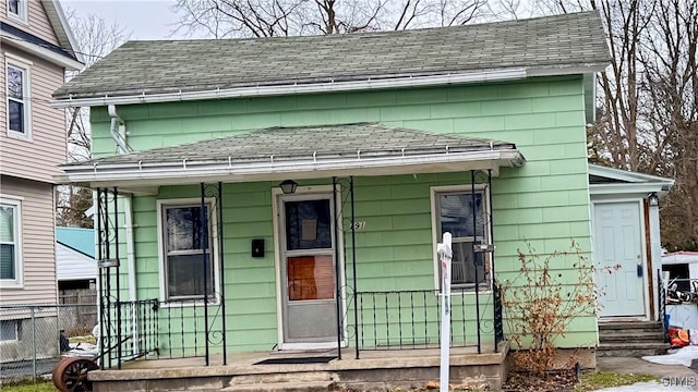 exterior space featuring entry steps, covered porch, roof with shingles, and fence