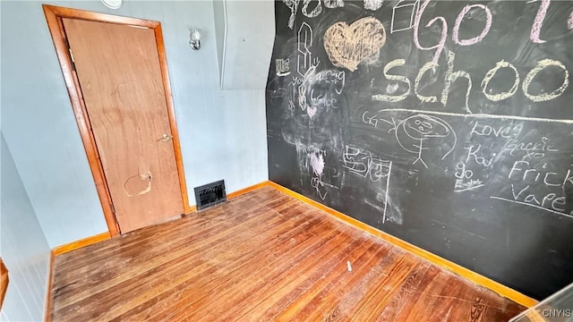 empty room with visible vents, baseboards, and wood finished floors