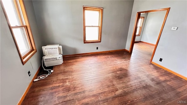 empty room featuring a wealth of natural light, wood-type flooring, and baseboards