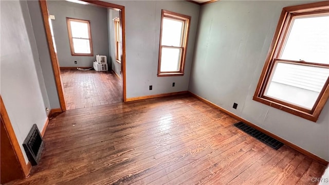 unfurnished room featuring hardwood / wood-style flooring, visible vents, and baseboards