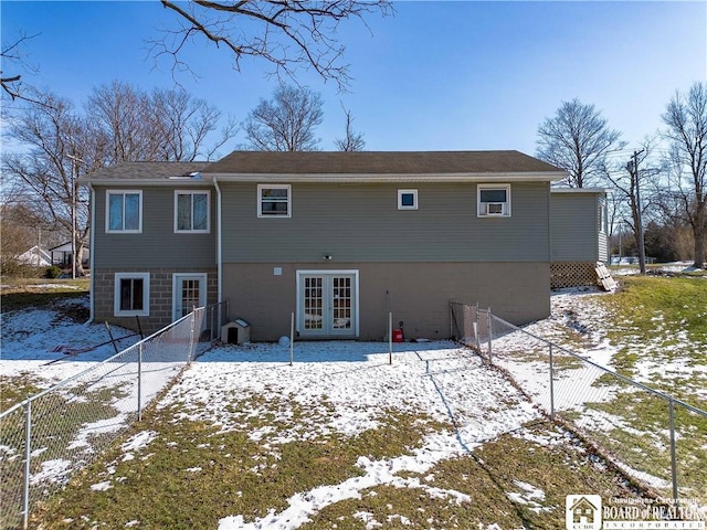 snow covered property featuring a fenced backyard, french doors, cooling unit, and a patio