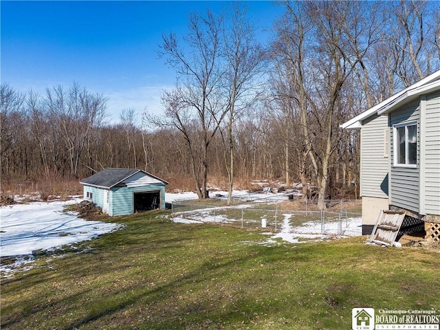 yard covered in snow with fence, an outbuilding, a storage shed, and a garage