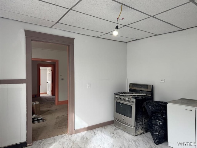 kitchen featuring marble finish floor, a paneled ceiling, stainless steel gas range, baseboards, and fridge