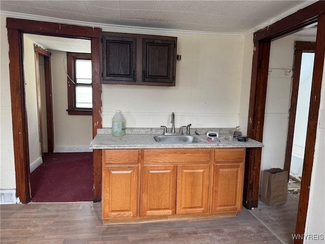 kitchen featuring a sink, visible vents, light wood-style floors, light countertops, and brown cabinetry