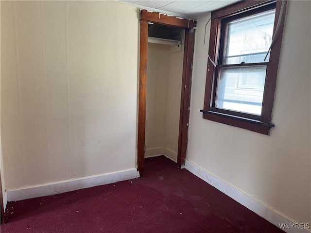 carpeted spare room featuring plenty of natural light and baseboards