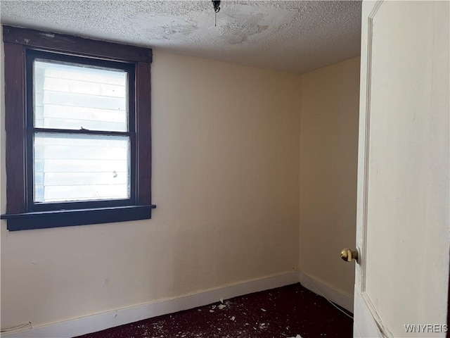 empty room featuring a textured ceiling and baseboards