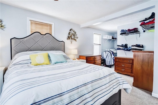 bedroom featuring light carpet and beamed ceiling