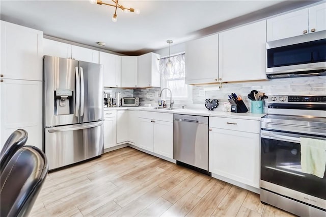 kitchen featuring a sink, stainless steel appliances, light countertops, light wood-type flooring, and backsplash