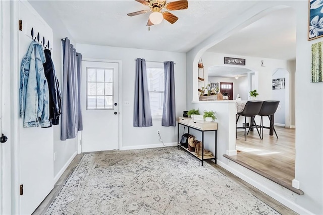 foyer entrance featuring light wood finished floors, baseboards, and a ceiling fan