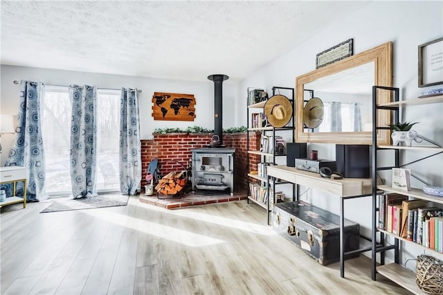 living area with a wood stove, a textured ceiling, and wood finished floors