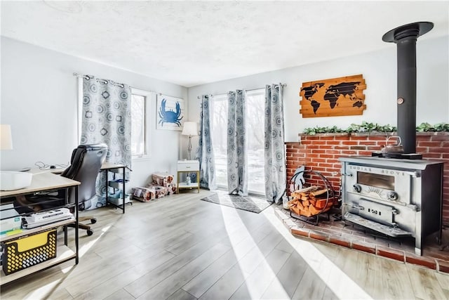 office area featuring a wood stove, a textured ceiling, and wood finished floors