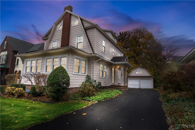 colonial inspired home featuring a garage, a chimney, an outbuilding, and a gambrel roof