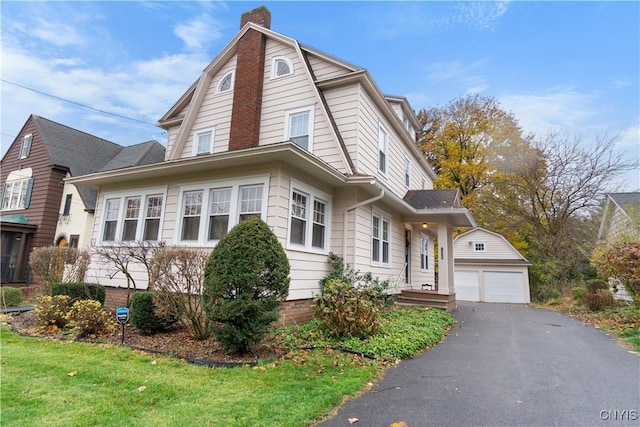 colonial inspired home with a garage, an outbuilding, a chimney, and a gambrel roof