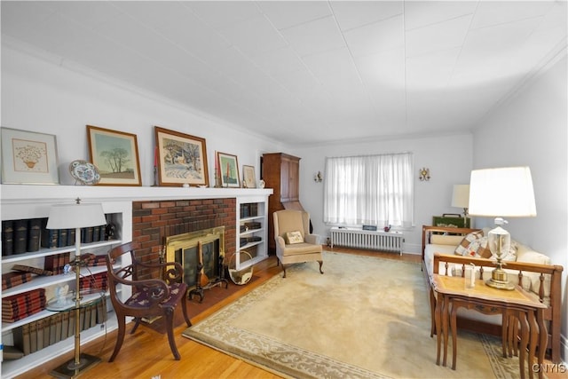 living area featuring radiator, a fireplace, and wood finished floors