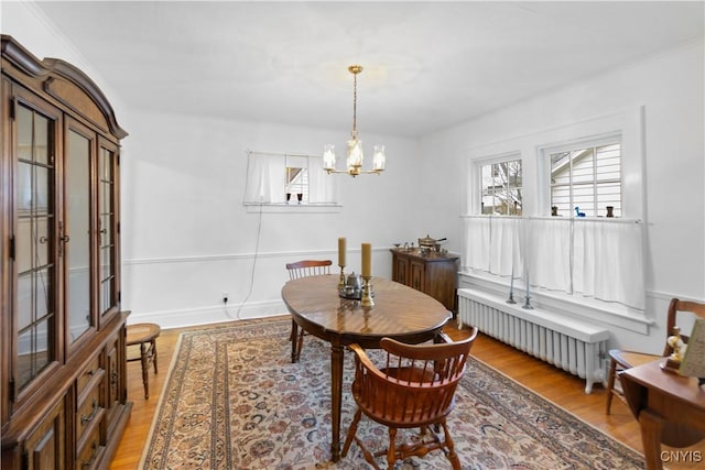 dining space with light wood-type flooring, radiator heating unit, and a notable chandelier