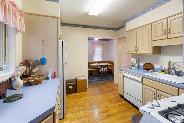 kitchen featuring light brown cabinets, white appliances, a sink, light countertops, and light wood-type flooring