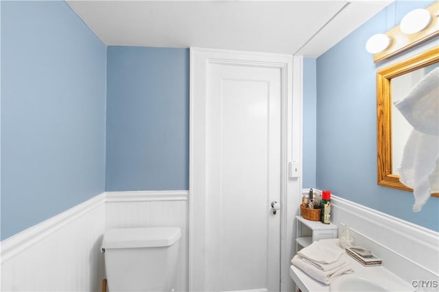 half bathroom featuring a wainscoted wall and toilet