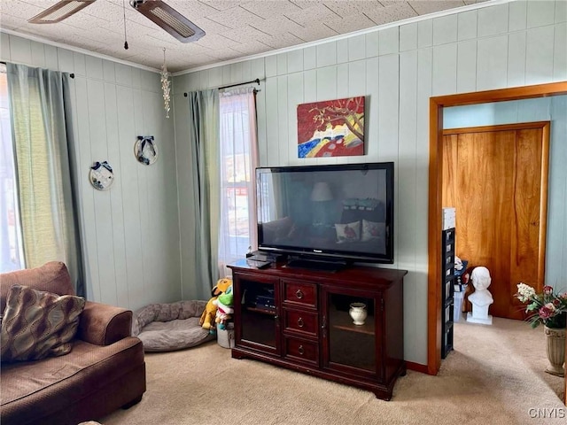 carpeted living room with ceiling fan and ornamental molding