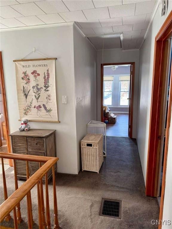 hallway with stairs, carpet floors, ornamental molding, and visible vents