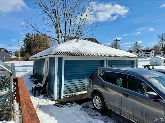 snow covered garage with a detached garage and fence