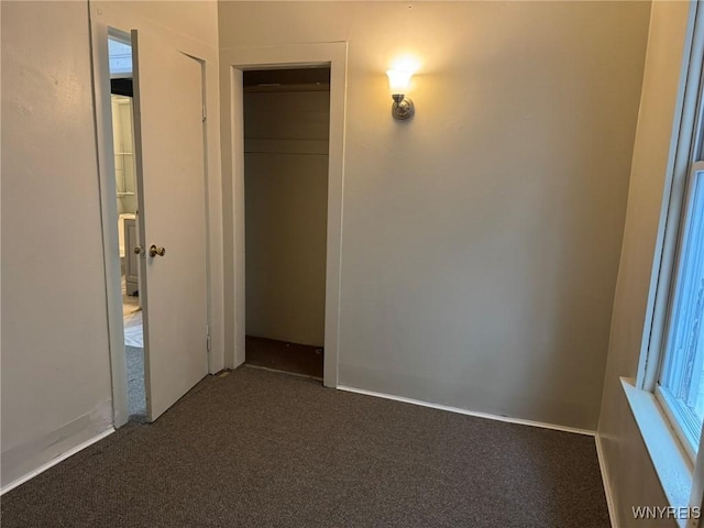 unfurnished bedroom featuring dark colored carpet and a closet