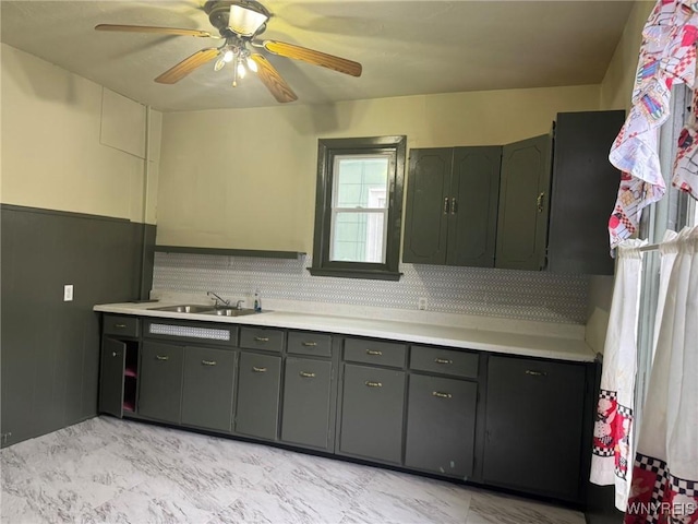 kitchen featuring backsplash, gray cabinets, light countertops, and a sink