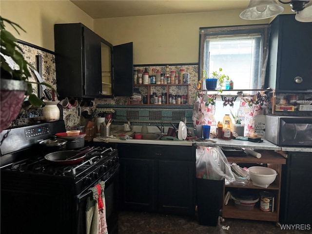 kitchen featuring black gas range oven, stainless steel microwave, light countertops, dark cabinetry, and a sink