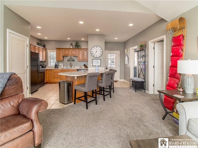 kitchen with recessed lighting, open floor plan, range, freestanding refrigerator, and a kitchen bar