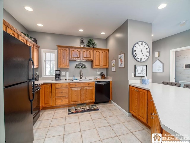 kitchen with a peninsula, black appliances, light countertops, and a sink