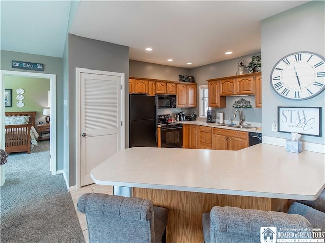 kitchen featuring light colored carpet, a peninsula, a sink, light countertops, and black appliances