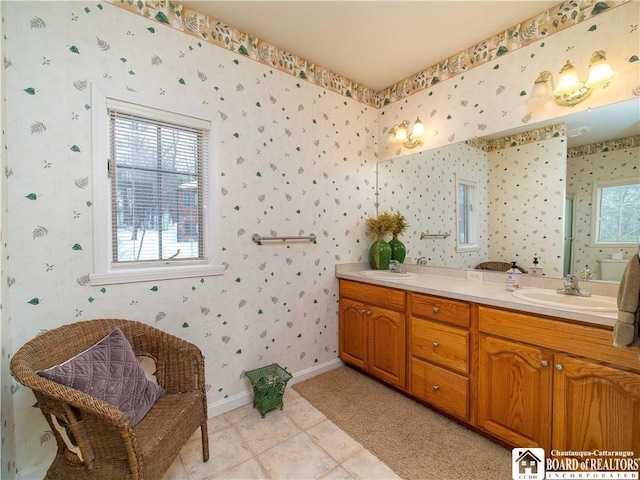 full bath with double vanity, wallpapered walls, baseboards, tile patterned floors, and a sink