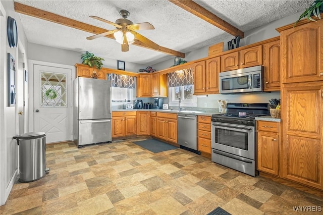 kitchen featuring brown cabinetry, appliances with stainless steel finishes, light countertops, and beam ceiling